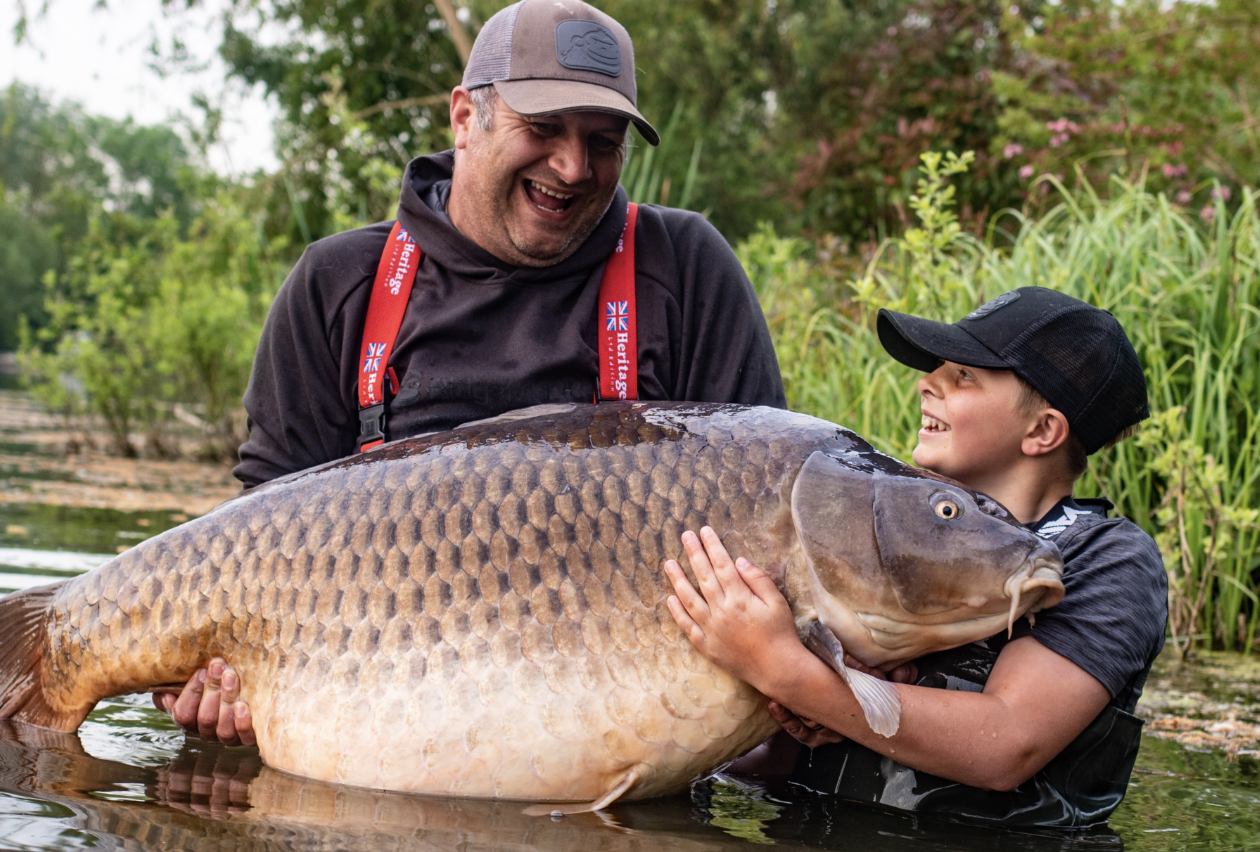 large wild common carp being held by man and child